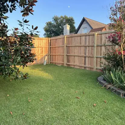 A straight wood privacy fence along a garden